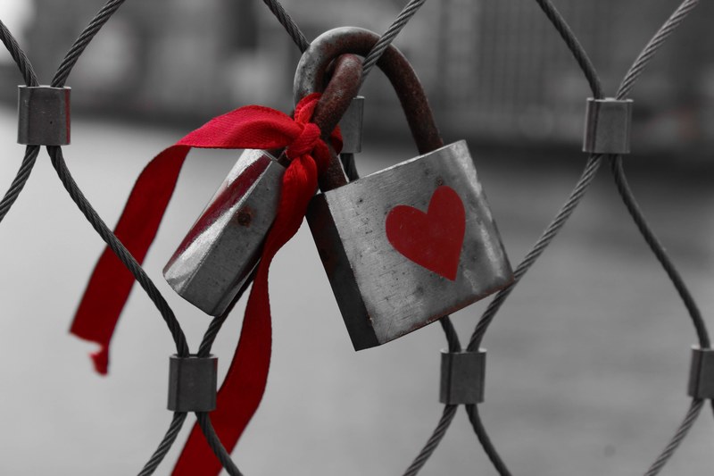padlock on a wire fence has red heart painted on it and ribbon attached, locked hearts 4k