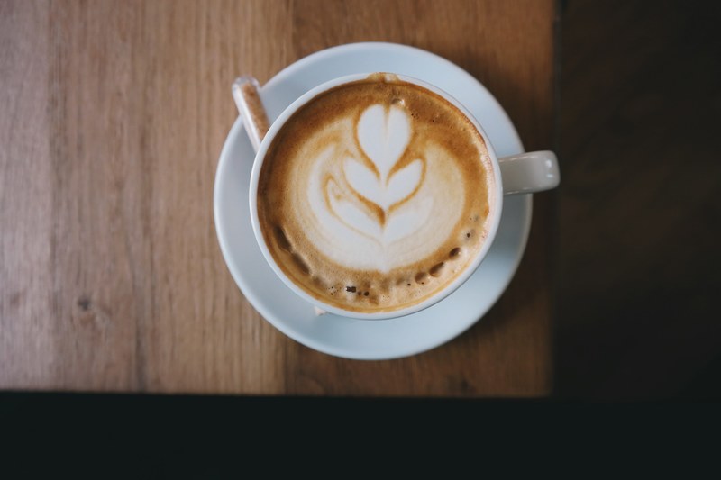 an overhead shot of latte art in a white cup on a saucer, foamy latte art 4k