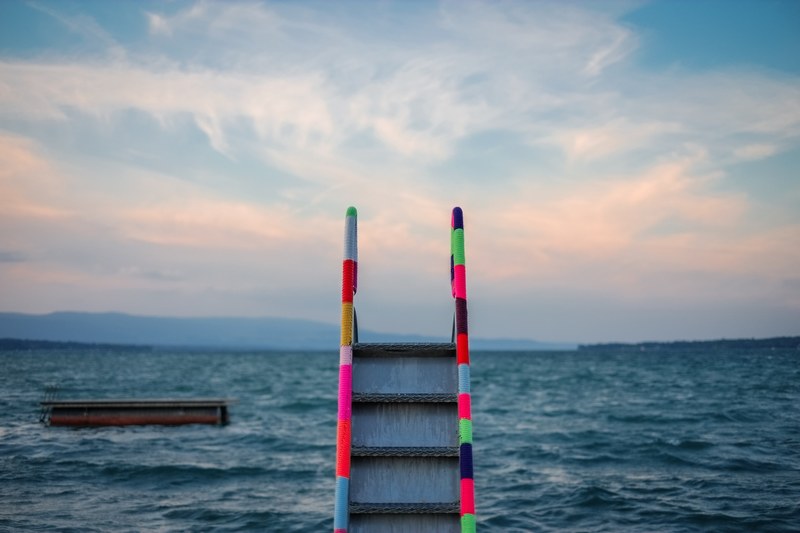 a striped colored ladder staircase leading to the ocean water, colorful ladder to ocean 4k