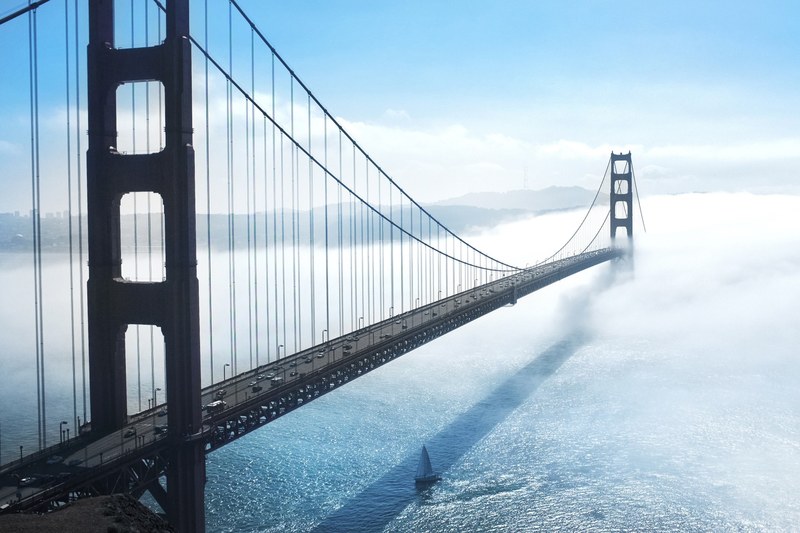 suspension bridge over crystal blue waters on a cloudy day, bridge over calm waters 4k