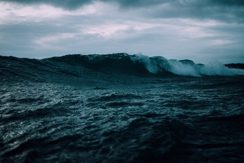 a wave rolling on a turbulent sea beneath a moody cloudy sky at omaha, waves under a moody sky 4k
