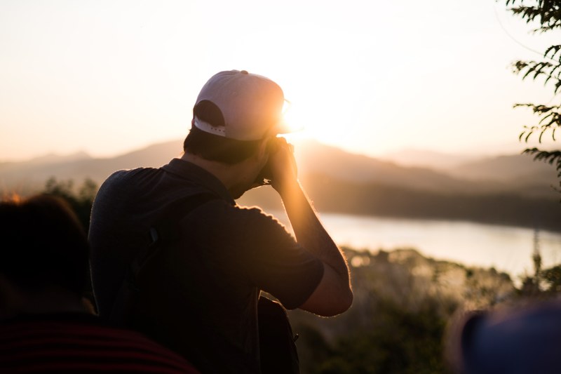 photographer taking a picture of the sunset over mountains, photographer taking a sunset shot 4k