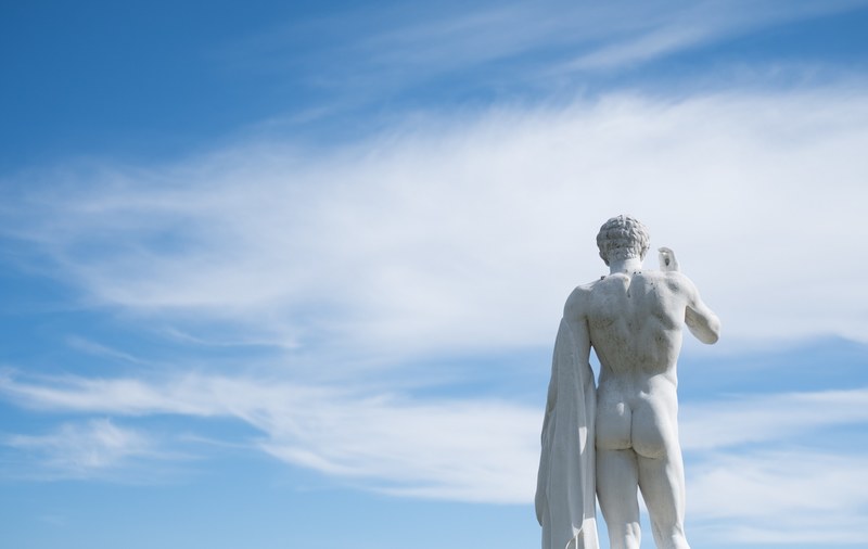 back of a nude art statue at a museum against a blue cloudy sky, statue in the sky 4k
