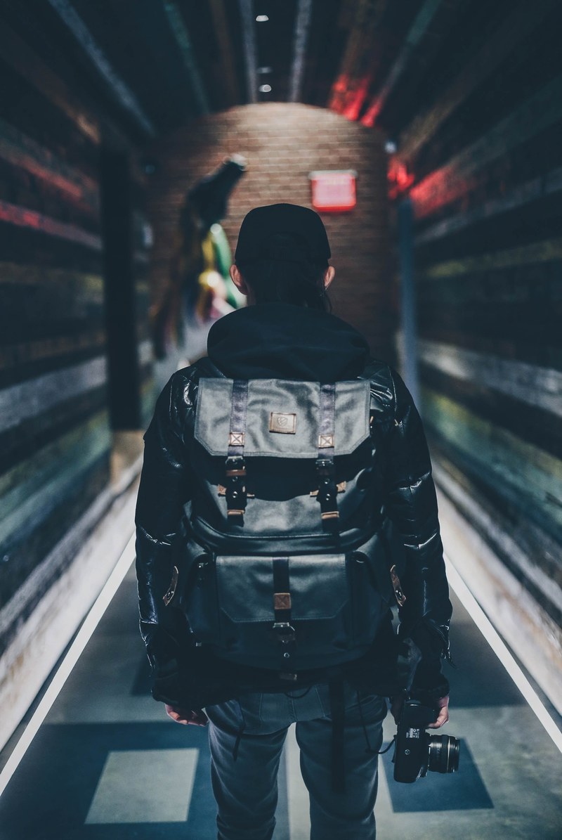 person in a backpack walks down a dark urban tunnel, langly alanking dizzy_d718 4k