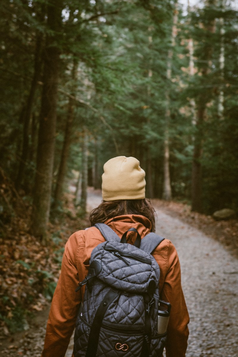 a person in a cap and backpack hikes down a trail at lula lake land trust, person hiking on trail 4k