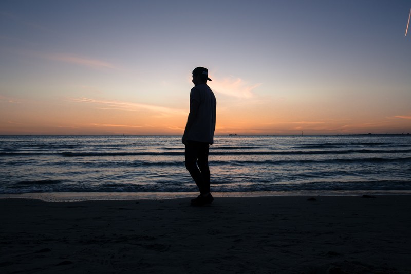 silhouette of a man standing on st kilda beach during a late evening sunset, man standing beach silhouette 4k