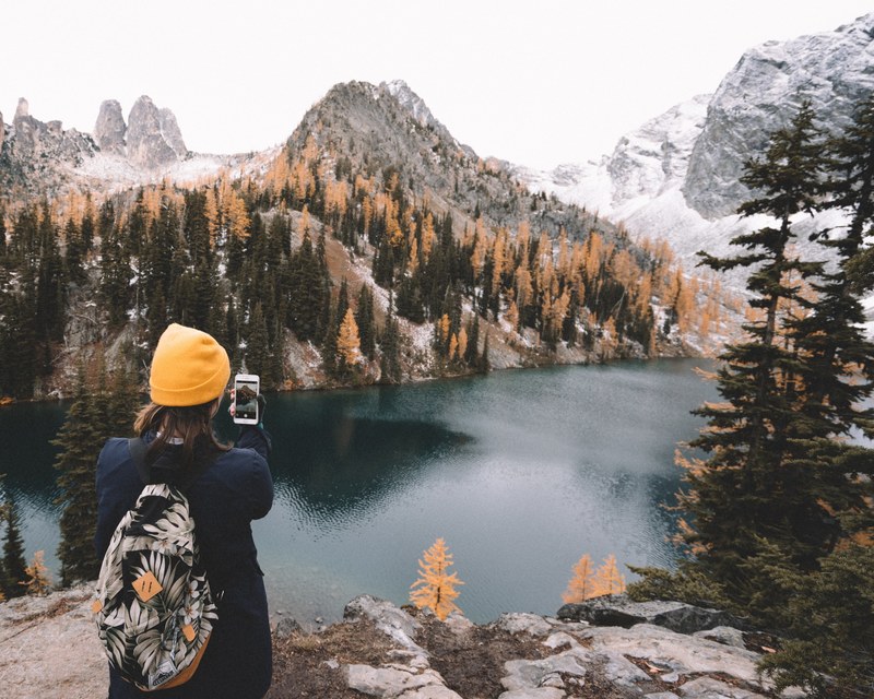 a person taking a photograph of the lake mountains and trees in north cascades national park, photographing a mountain lake 4k