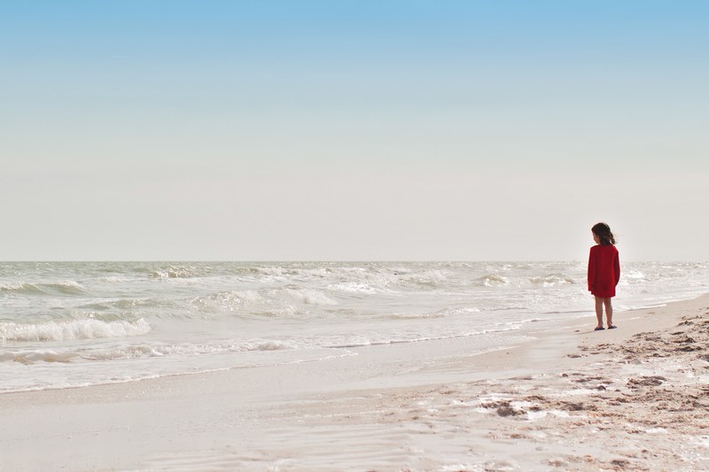 child standing on the sandy beach looking at the ocean waves at sanibel, child on the beach 4k