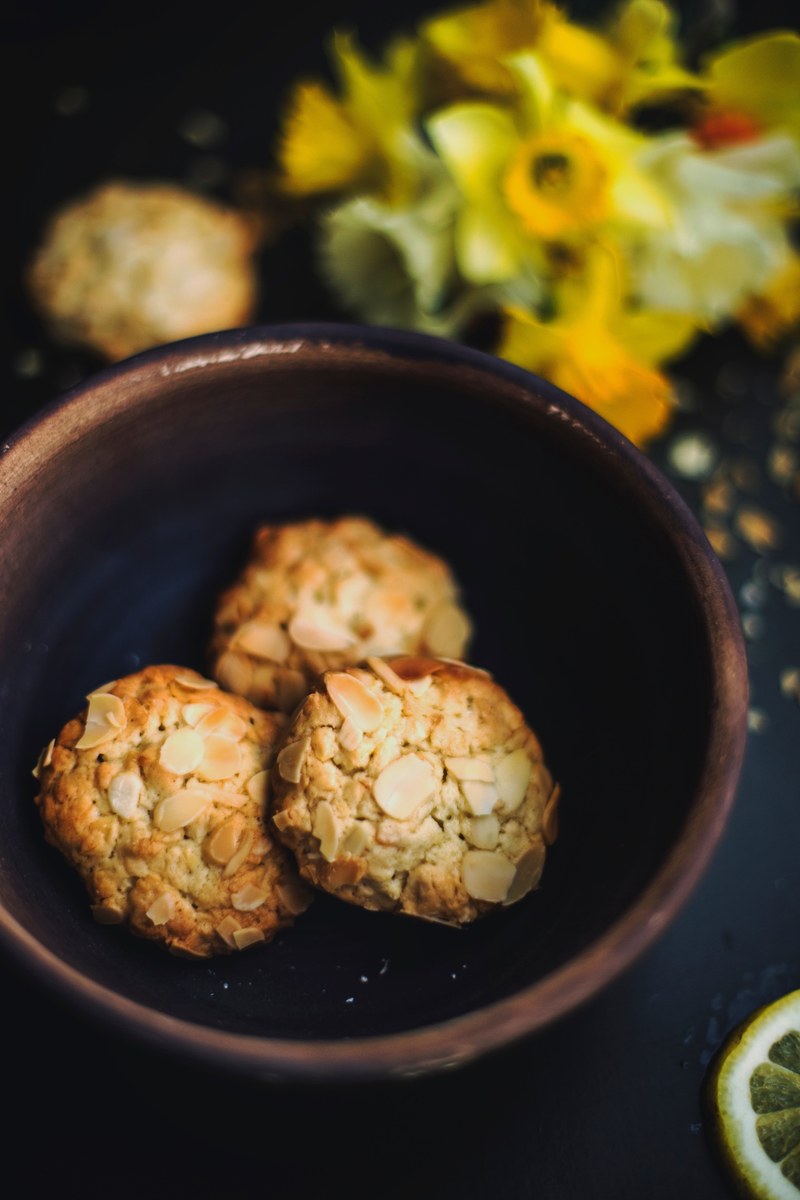 almond cookies in a bowl with daffodils in the background, cookie snacks 4k