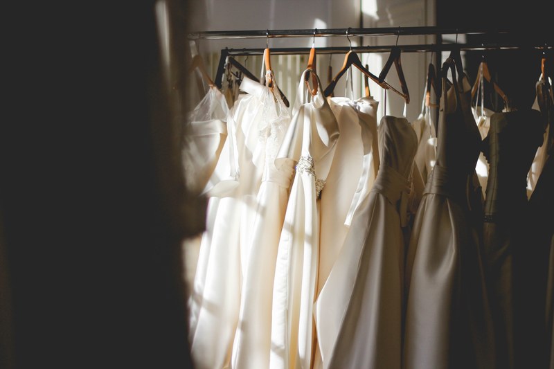 white and beige dresses on hangers in a store, white dressers on hangers 4k