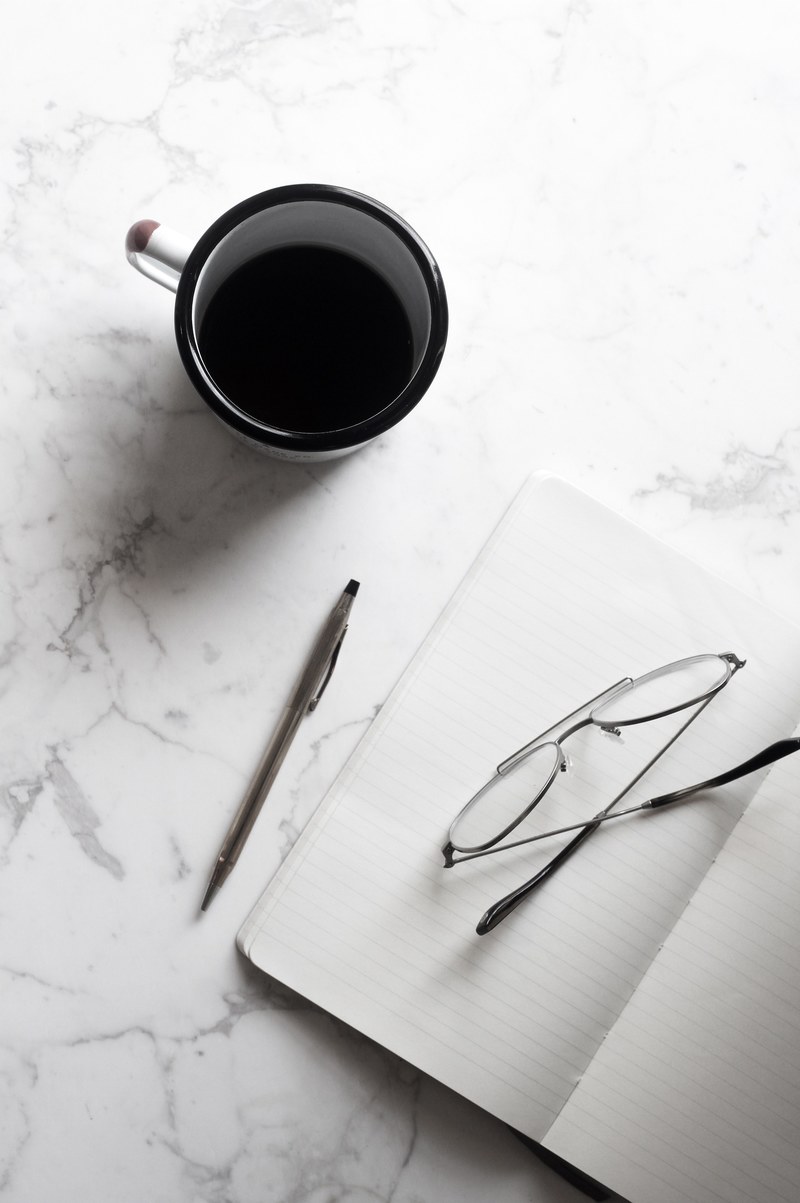 a cup of black coffee next to a notebook with a pencil and pair of glasses, _black coffee notebook 4k