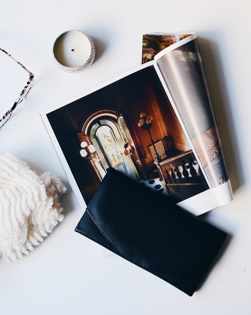 a flatlay with a magazine with large photographs a purse and a candle, saturday morning at home 4k