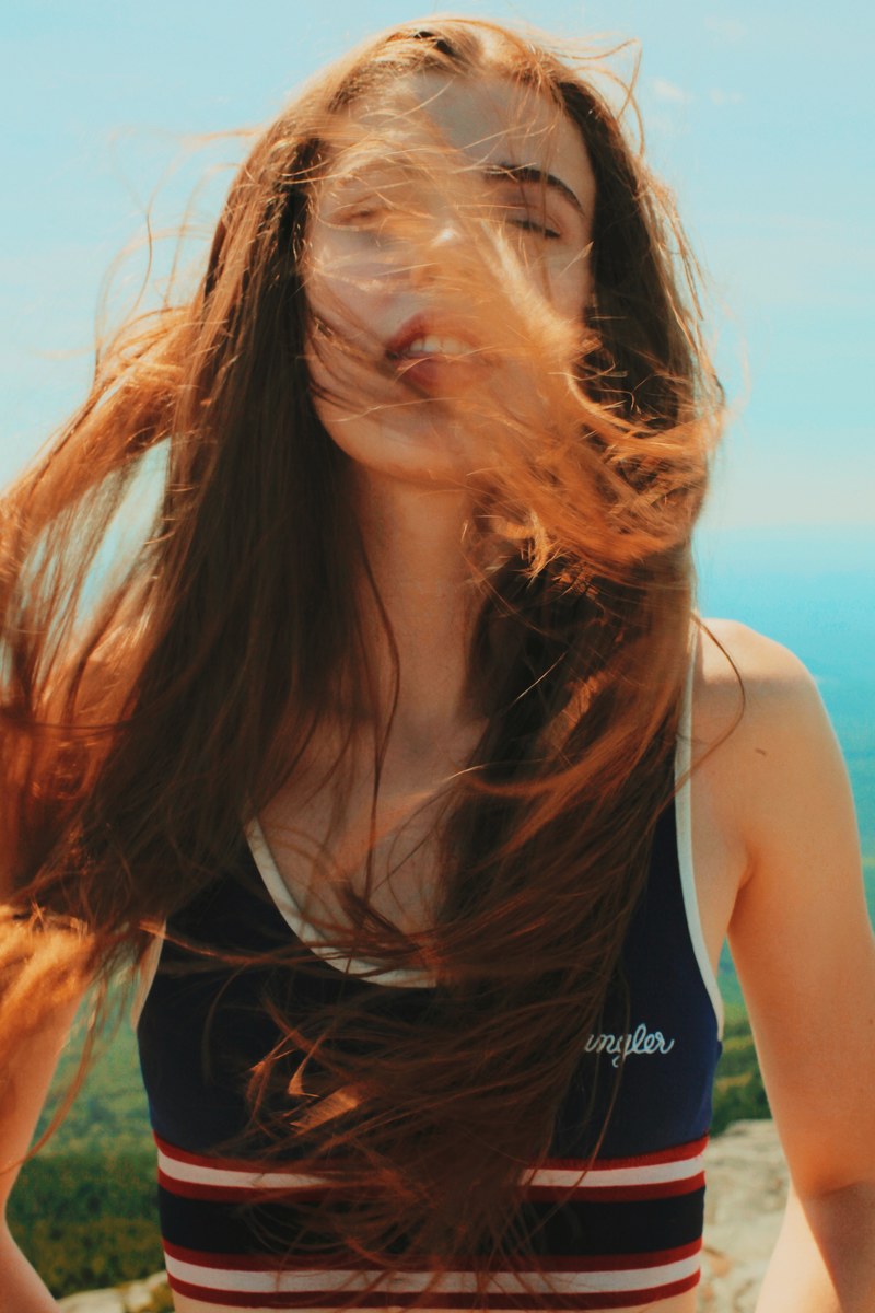 a woman with her red hair in her face at mount monadnock, moutaintop breeze 4k