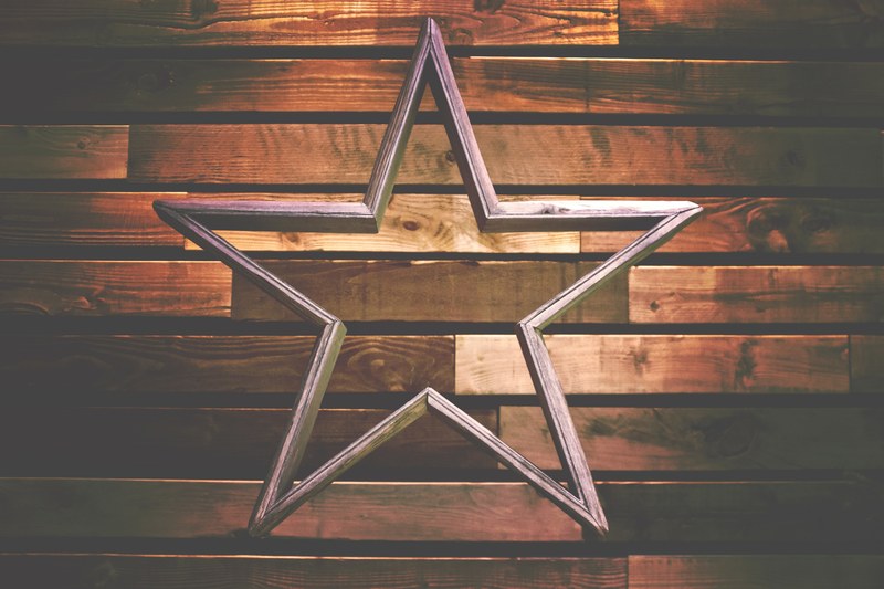 a wooden decoration in the shape of a hollow star against a wooden wall, wooden star 4k