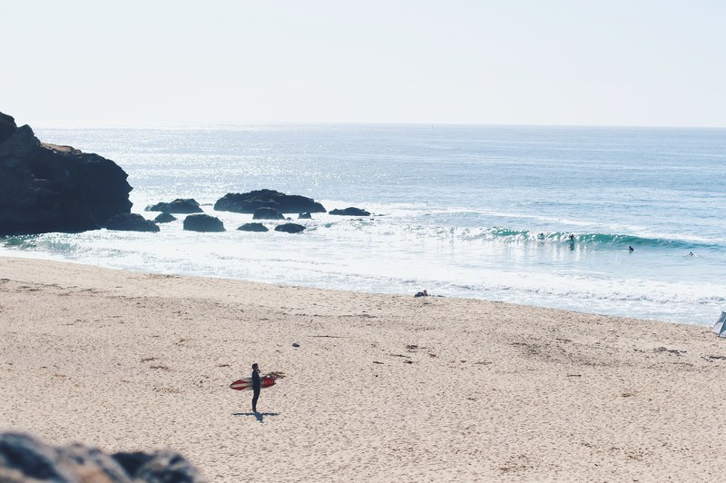 surfer standing on the sand beach looking at the waves at montara beach, montara surf check 4k