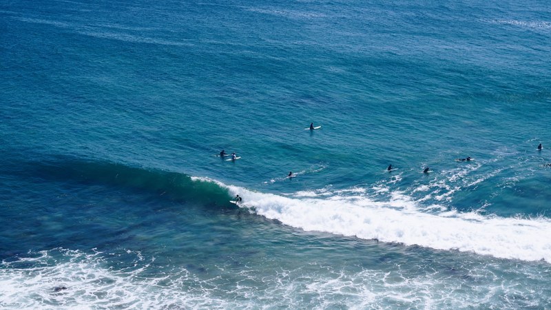 drone view of the surfers in the blue ocean at zuma beach, surfers in the blue sea 4k