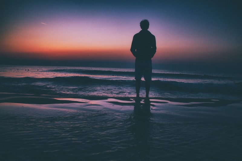 man with hands in pockets standing towards ocean during sunset in eforie nord, man low waves sunset 4k