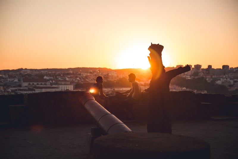 couple sitting near a cannon at st georges castle in lisbon, sunset at castelo de s_ jorge lisbon 4k