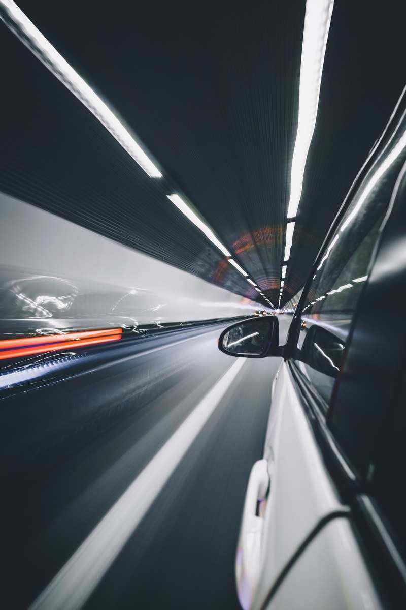 long exposure photo of a white car driving through a tunnel with traffic lights, long exposure traffic tunnel 4k