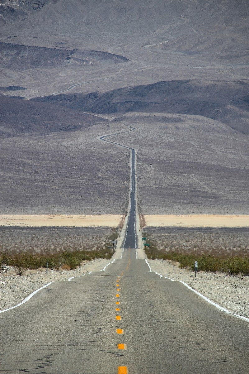 empty rural highway road creates a line through the desert terrain, driving through desert terrain 4k