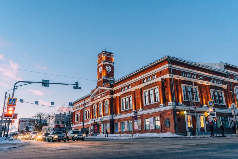 view of an intersection with traffic and a building with a clock tower in the background, cherepovets intersection at dawn 4k