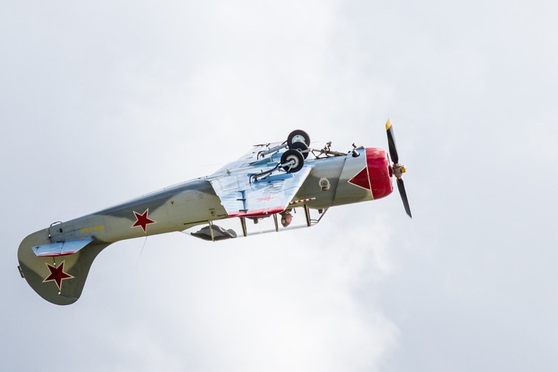 a vintage fighter jet plane flying upside down under a cloudy sky, aeroshow 4k