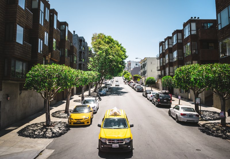 yellow ford taxi car on a sunny urban avenue with parked cars on both sides, yellow ford taxi car on a sunny avenue 4k
