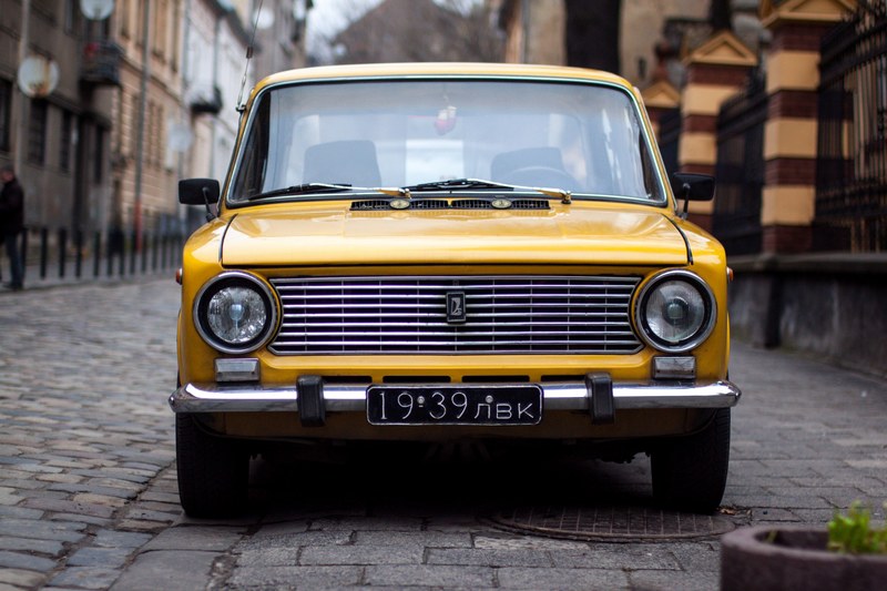 an old vintage yellow car parked on a cobblestone street, yellow vintage car 4k
