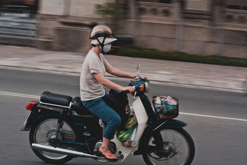 man riding a motorcycle with grocery plastic bags while wearing a mouth mask and a hat, speed 4k