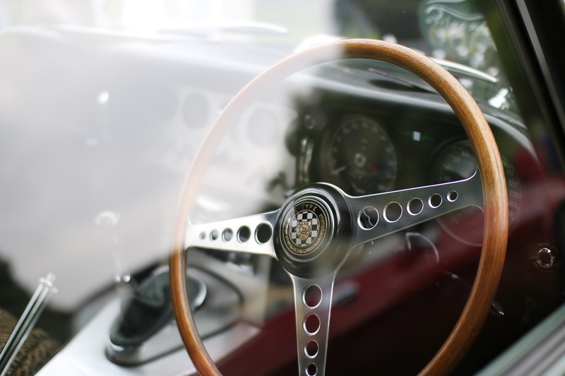 interior of vintage car with wooden steering wheel from outside of window with reflection windsor, through the window 4k