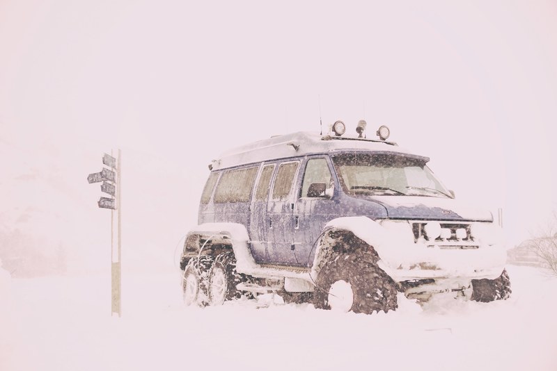 a 4x4 vehicle with flood lights driving through the snow in iceland, waiting in snow 4k