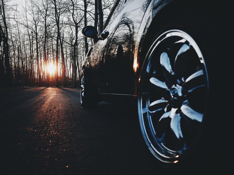 black car chrome rim on an asphalt road in a leafless forest on sunset, chrome rim on a black car on sunset 4k