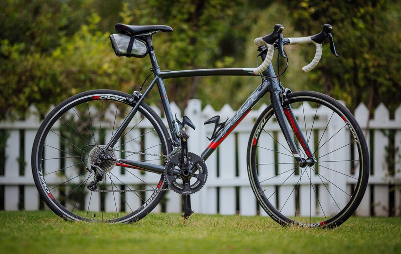 a close up shot of a standard pedal bike with curved handlebars sitting in front of a white picket fence, bike and white picket fence 4k