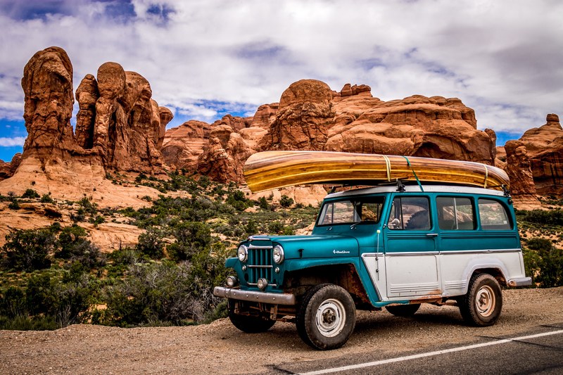 retro jeep with wooden canoe on roof at side of road in arches national park, retro jeep with canoe on roof 4k