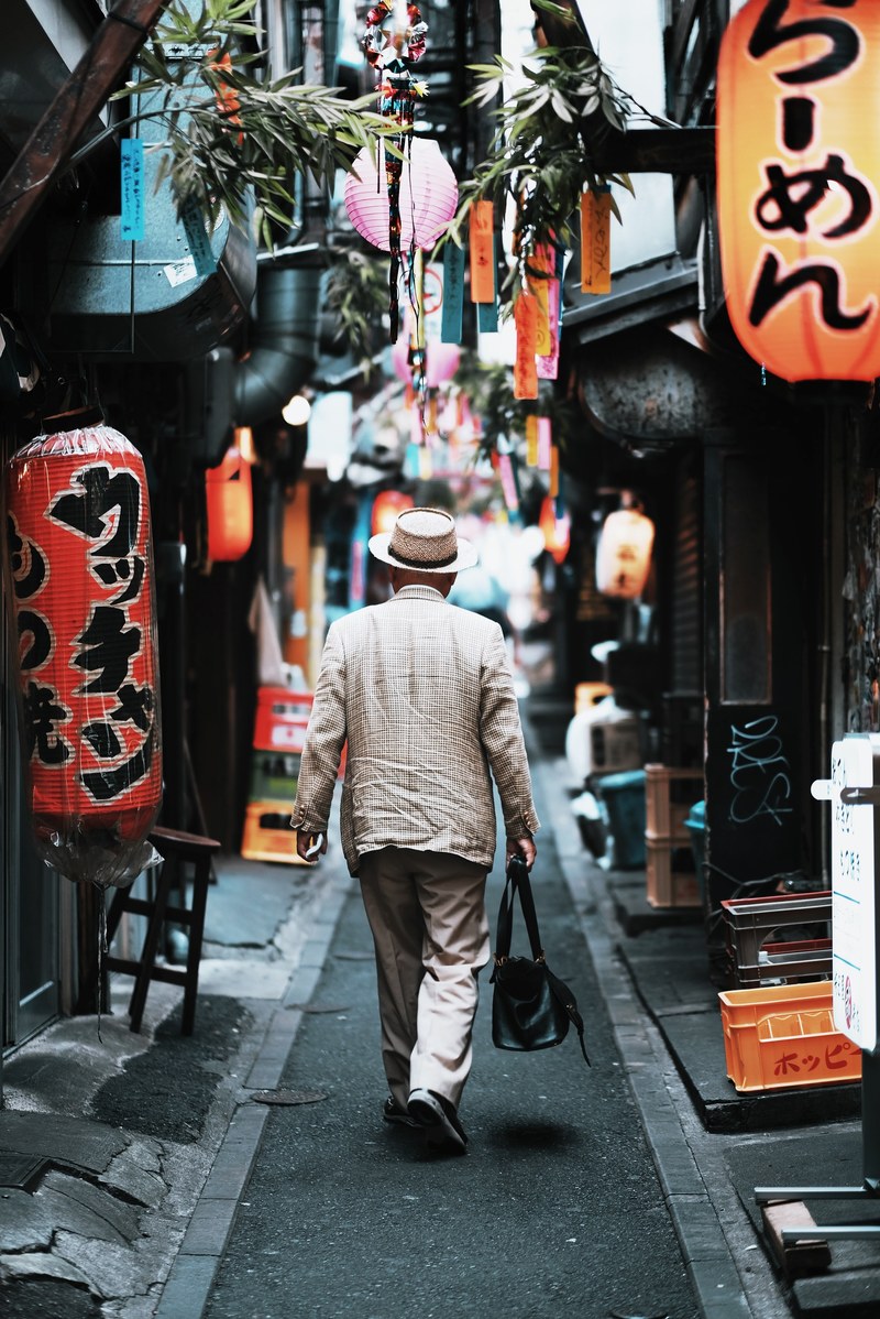 an elderly man in a suit in a narrow alley in tokyos shinjuku district, japan 2017 4k
