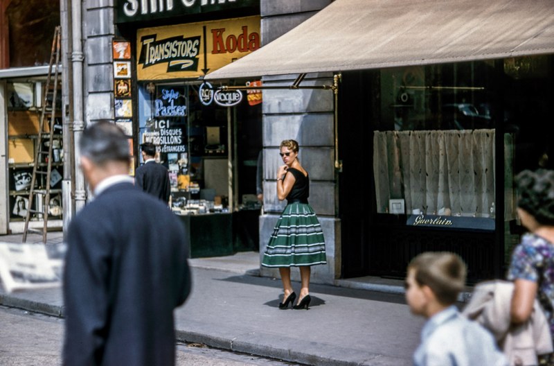 a woman in a green skirt in a french street looking back, retro french street 4k