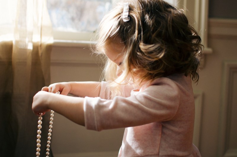 young girl with a pink shirt holder her mothers pearl necklace, great grandmas pearls 4k