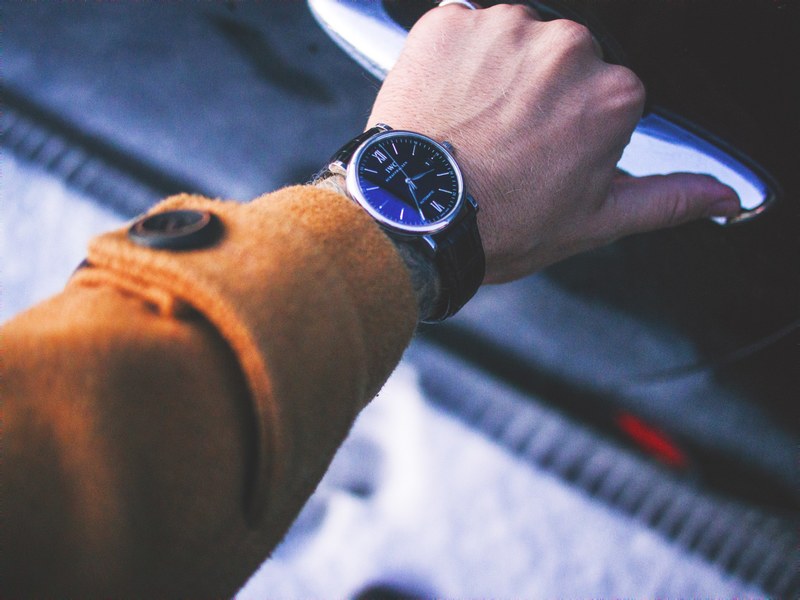 a mans arm in a brown jacket is holding the door handle of a car, _arm door handle car 4k