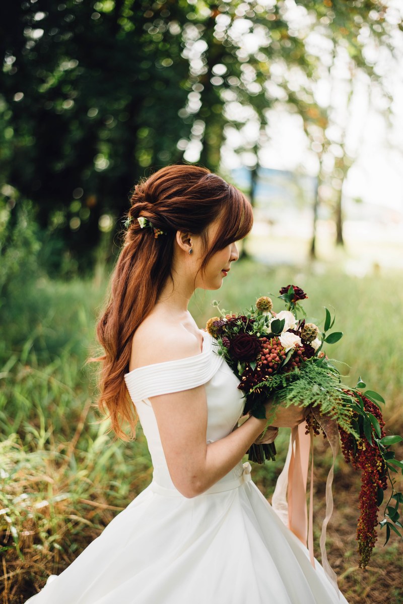 a woman in a bridal dress holding a bouquet of various flowers in front of her, bride with a diverse bouquet 4k