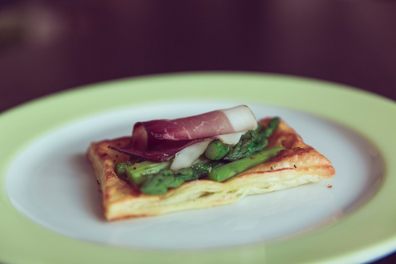 slice of pancetta and asparagus on a square of puff pastry laid on a clean white plate, pancetta and puff pastry 4k