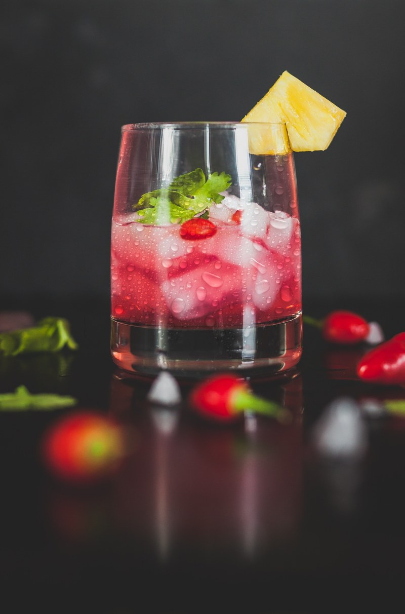 macro view of cocktail drink in a glass with ice garnished with pepper leaf and fruits, macro view of cocktail 4k