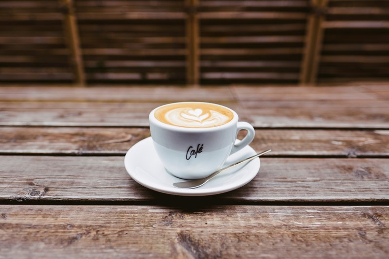 a cup of coffee with latte art on a saucer on a table, cup saucer and coffee art 4k