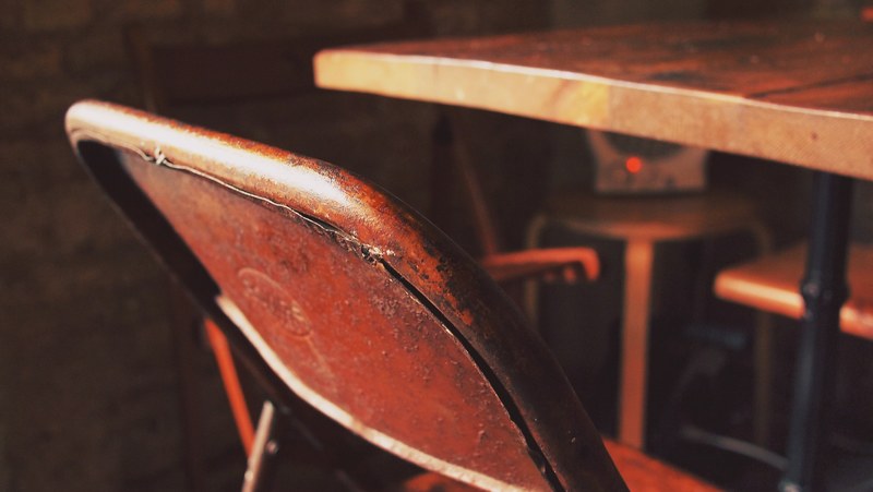 a used vintage chair and table with a radio in the background, a seat at the table 4k