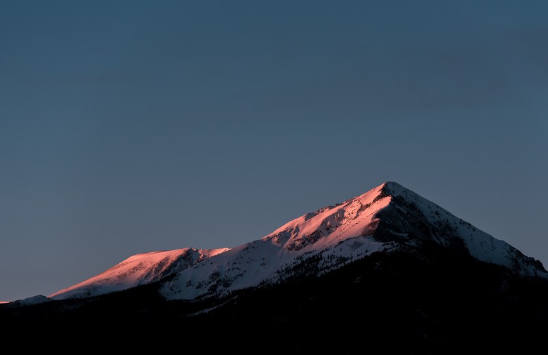 a snowy mountain with long wooded slopes in silverthorne during sunset, sunset over a summit in silverthorne 4k