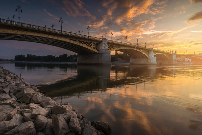the steel arch bridge and sky reflect into the still river in budapest during sunrise or sunset, a steel arch bridge over calm water 4k
