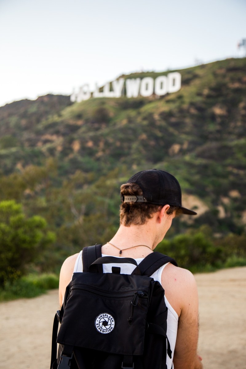 tourist with a backpack walks toward the hollywood sign in la, touring los angeles 4k