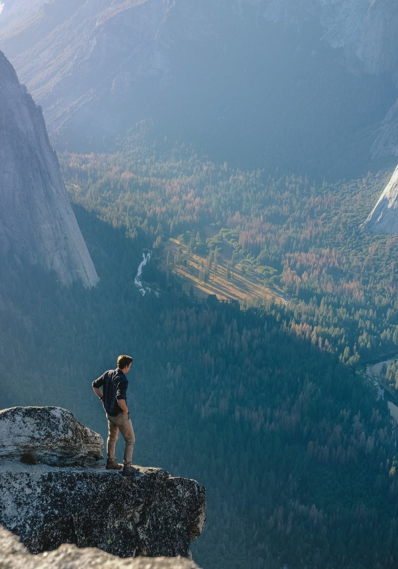 a man standing on a ledge with a view on the floor of yosemite valley, on a ledge overlooking yosemite 4k