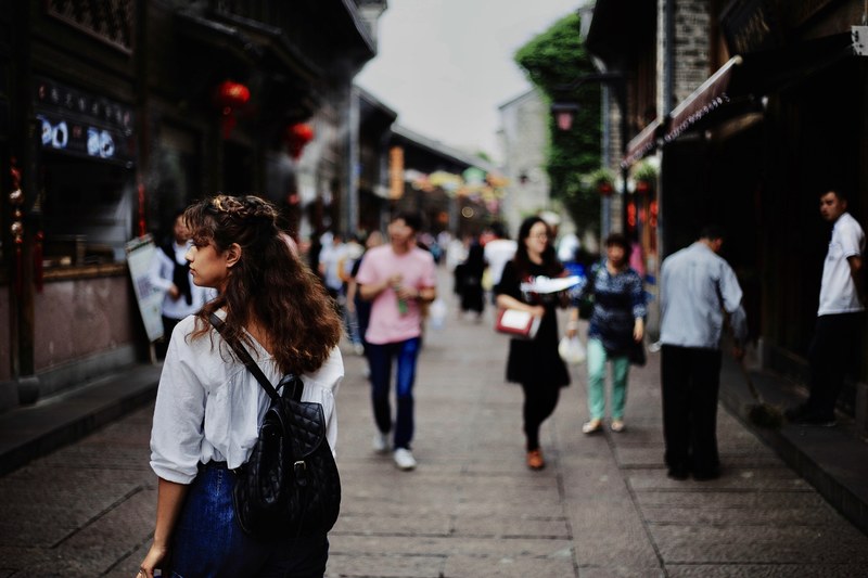 woman walks through a diverse crowd on a busy city street, lost in the ancient city 4k