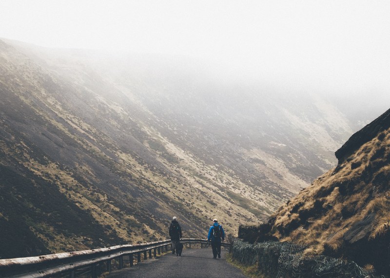 people walking the roads of peak district national park through fog, hiking past hills 4k