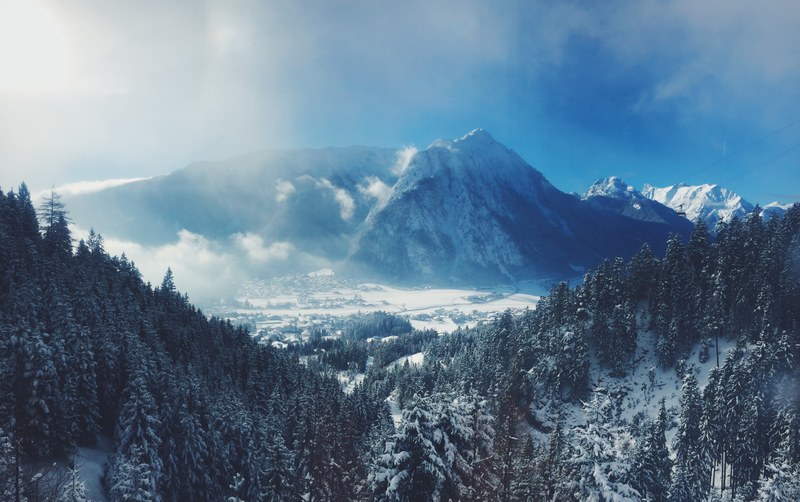 distant view of a snow capped mountain ridge towering over a valley, snowy mountains in tirol austria 4k